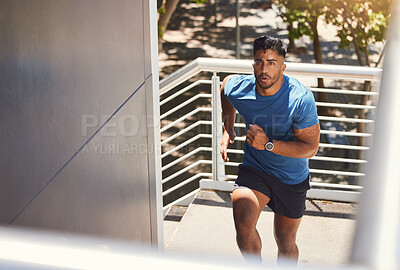 Handsome mixed race athletic man running up the steps on of a building while focused on his fitness. Hispanic male serious about his health while doing cardio and working on his speed and energy.