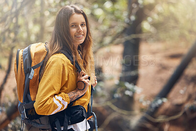 Buy stock photo One young active caucasian woman wearing a backpack while out hiking in the forest. Young brunette female walking alone in the woods. She loves being outdoors in nature. Hiking is her favourite hobby