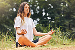 Young caucasian woman meditating while exercising outdoors. One female only practising yoga to stay calm and relaxed in body, mind and soul. Focused on breathing during workout at the park or forest