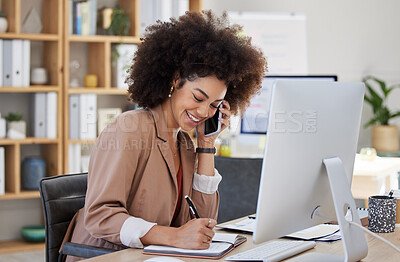 One young mixed race american businesswoman with an afro talking to clients with a cellphone and using a computer. Smiling hispanic creative professional networking and planning while using technology