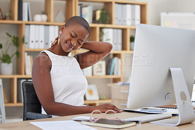 One young african american female businesswoman sitting at her desk in front of her computer experiencing neck pain and discomfort in her office. Young black woman suffering from muscles spasms and tension in her neck while massaging it to release tension