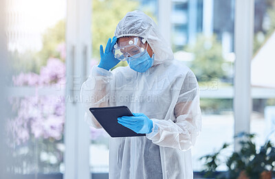 Buy stock photo Stressed and worried woman using digital tablet while wearing a protective hazmat suit to keep safe from covid and disease in hospital or lab. One female only struggling with a headache and challenge