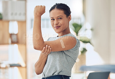 Buy stock photo Young happy mixed race woman showing and holding her arm with a bandaid after getting a vaccine. Beautiful and confident young woman playing a showing her muscles after getting a covid vaccine