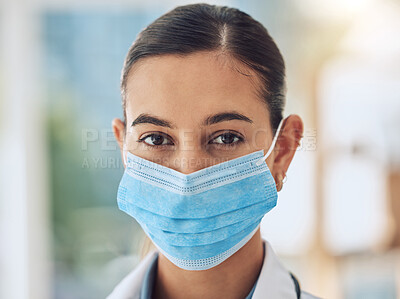 Buy stock photo Young female mixed race nurse wearing a mask to protect herself from covid disease while working at a hospital. Portrait of a young female hispanic doctor standing at a clinic 