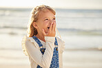 Close up view on a little young caucasian brunette girl making a shocked gesture with her hand while smiling and standing alone outside at the beach on a sunny summer day. Young girl looking surprised while on vacation , innocent and happy with the ocean