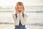 Close up view on a little young caucasian brunette girl making a shocked and astonished gesture with her hand while smiling and standing alone outside at the beach on a sunny summer day. Young girl looking surprised while on vacation , innocent and happy 