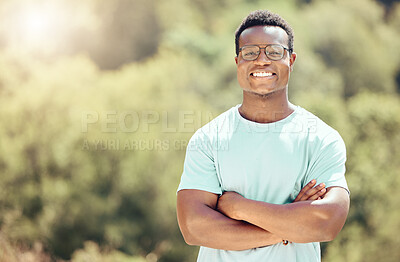 Buy stock photo One handsome young african american male wearing glasses and standing outside with his arms folded. Happy and confident black man smiling while spending the day outdoors in nature. I love summer