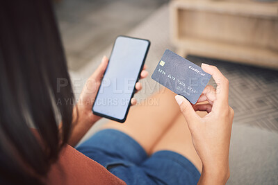 Closeup shot of an unrecognizable mixed race woman using a credit card while doing online shopping using her cellphone. young woman working on her finance and budget while sitting on a sofa at home