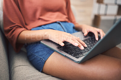 Closeup shot of an unrecognizable mixed race woman using a laptop while doing remote work from the couch. Young female doing freelance work while using the internet for research and sending an email