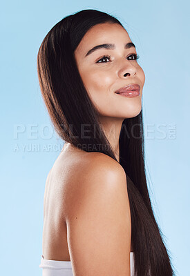 One beautiful young hispanic woman with healthy skin and sleek long hair smiling against a blue studio background. Happy mixed race model with flawless complexion and natural beauty