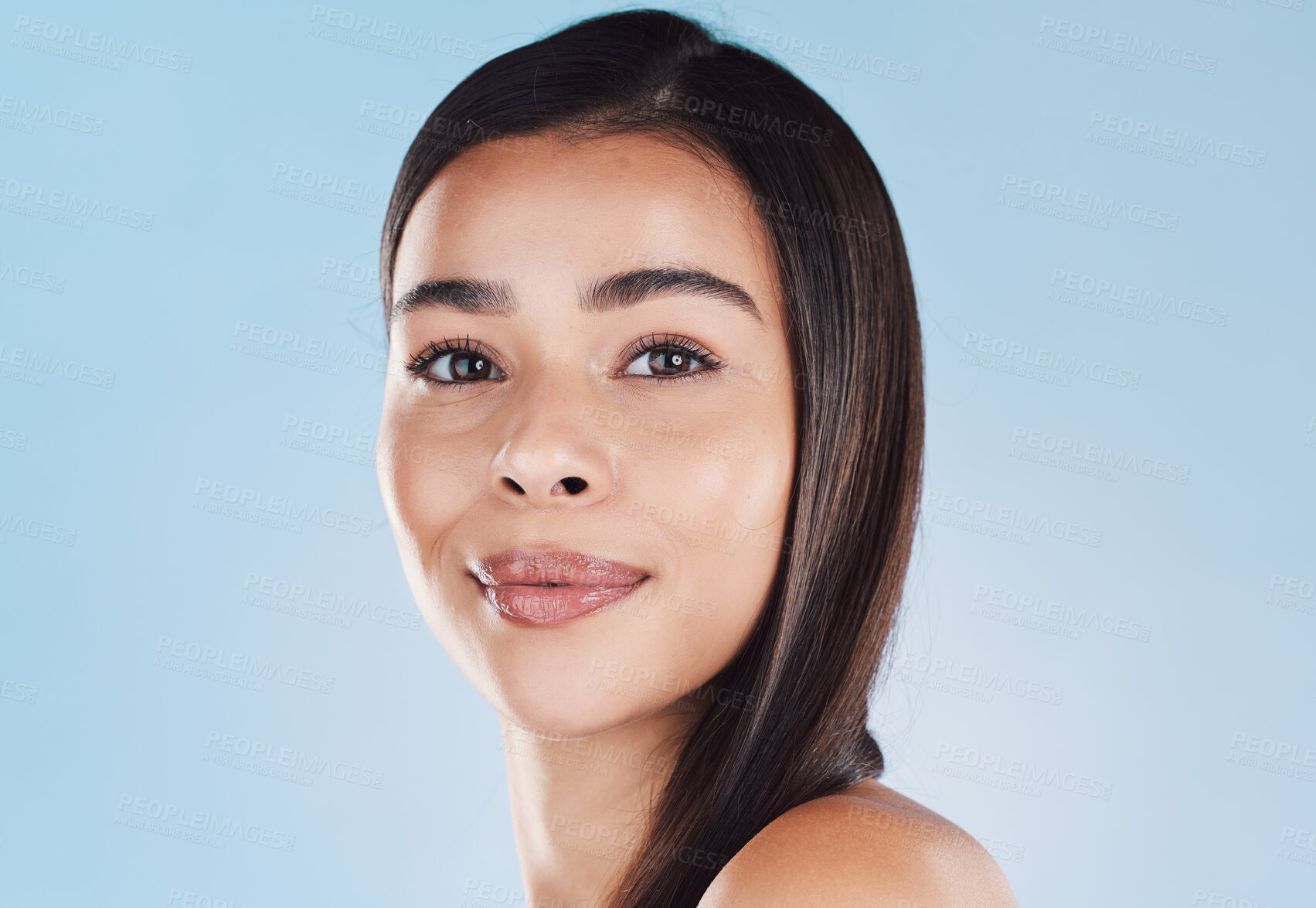 Buy stock photo Portrait of one beautiful young hispanic woman with healthy skin and sleek hair posing against a blue studio background. Mixed race model with flawless complexion and natural beauty
