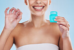 Beautiful young mixed race woman using dental floss isolated in studio against a blue background. Attractive female flossing her teeth for oral and dental hygiene and gum health, and a big smile