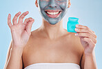 Beautiful young mixed race woman flossing her teeth with dental floss for oral hygiene isolated in studio against a blue background. Fresh and clean female out the shower, wearing a face mask peel