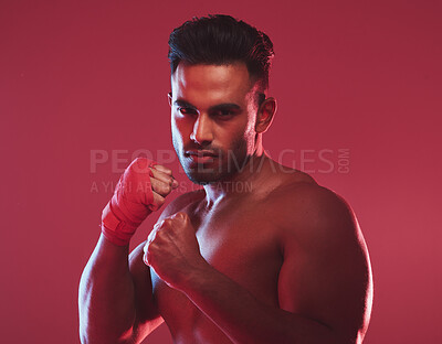 Buy stock photo One strong indian boxer wearing gloves and standing with fists in boxing stance ready to fight against a red studio background. Fierce muscular and topless man about to punch, hit and jab an opponent