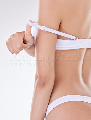 Rear view of one unrecognizable model posing in underwear against a white background studio. Unknown hispanic female removing her bra while showing her thick shape in a studio