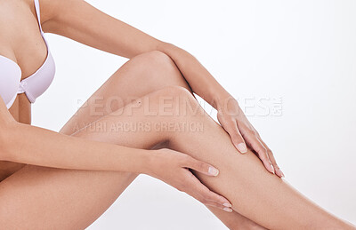 Closeup of unrecognizable woman posing in underwear against a white studio background. One female only feeling confident while showing her hairless, smooth legs after hair removal or epilation