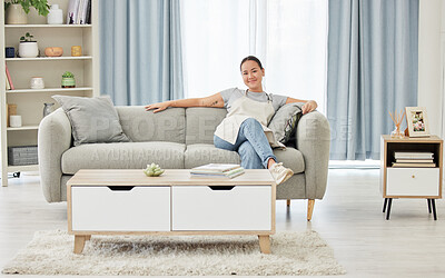 A happy smiling mixed race woman relaxing on the sofa after cleaning her apartment. One Asian woman sitting on the couch and taking a break after completing her chores