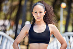 Portrait of one confident young mixed race woman standing with hands on hips ready for exercise outdoors. Determined female athlete looking focused and motivated for training workout