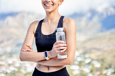 Closeup of one fit mixed race woman taking a rest break to drink water from bottle while exercising outdoors. Female athlete quenching thirst and cooling down after running and training workout