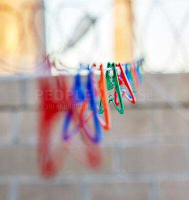 Closeup of a group of colourful clothing pegs on a washing line outside during the day. Plastic pegs used to hang laundry and linen for drying as part of household and domestic chores