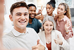 Group of cheerful diverse businesspeople taking a selfie together at work. Happy caucasian businessman showing a thumbs up while taking a photo with his content colleagues