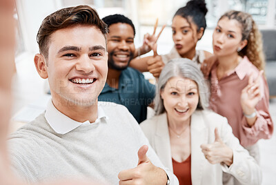 Buy stock photo Group of cheerful diverse businesspeople taking a selfie together at work. Happy caucasian businessman showing a thumbs up while taking a photo with his content colleagues