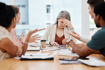 Group of businesspeople having a meeting together in a boardroom at work. Stressed mature caucasian businesswoman suffering from a headache while her colleagues talk