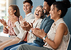 Group of cheerful businesspeople clapping while sitting in a row in a meeting together. Happy business professionals motivating each other while sitting in a waiting room together in an office