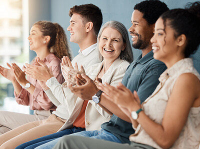 Group of cheerful businesspeople clapping while sitting in a row in a meeting together. Joyful business professionals motivating each other while sitting in a waiting room together in an office