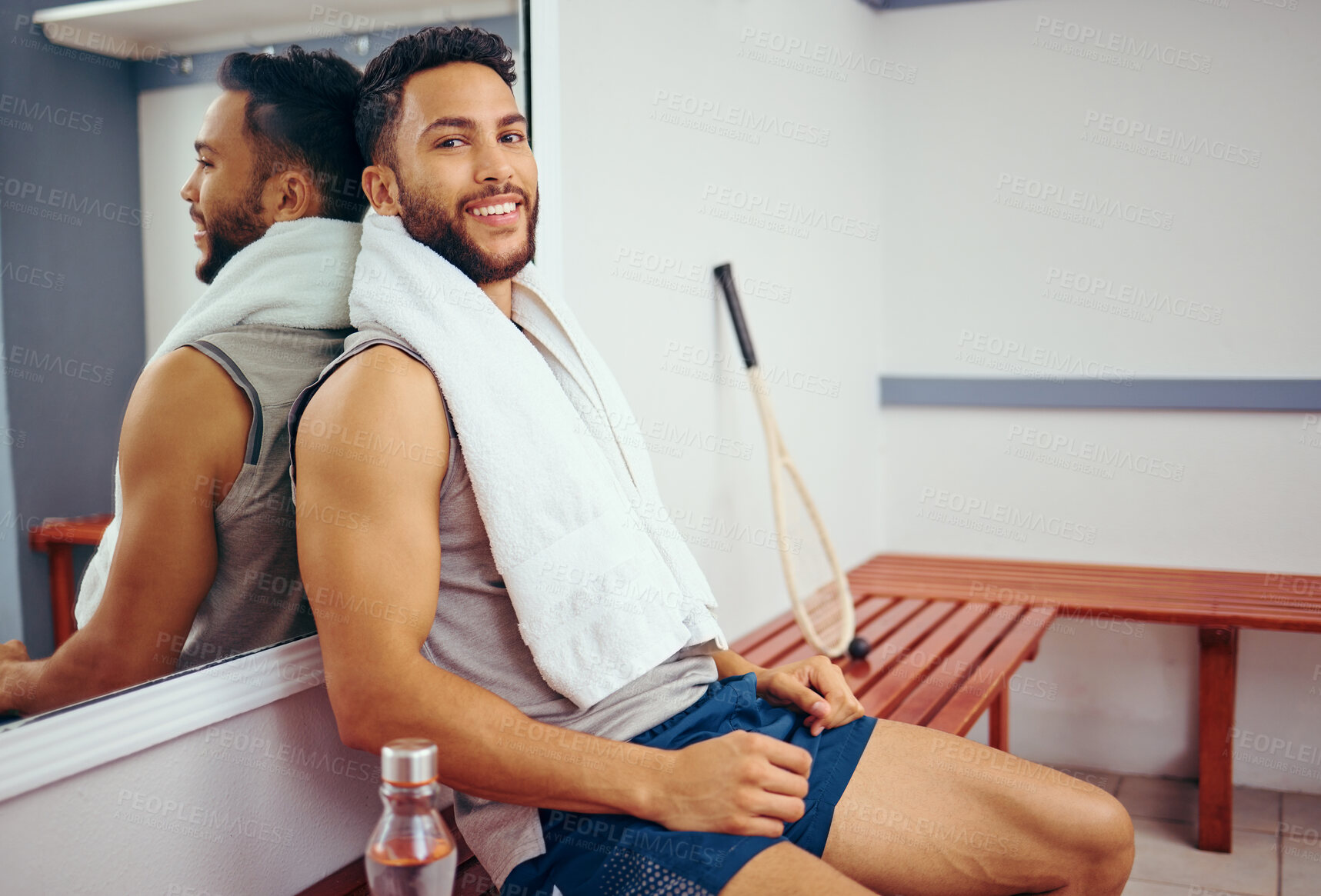 Buy stock photo Young athlete sitting in a gym locker room. Mixed race athlete taking a break from his workout. Portrait of smiling fit man relaxing in his gym. Hispanic player resting after a match