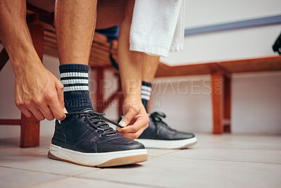 Buy stock photo Squash player tying his shoe laces in his gym locker room. Hand of a mixed race player preparing for a match. Closeup of squash player tying the laces of his sport sneaker in the locker room