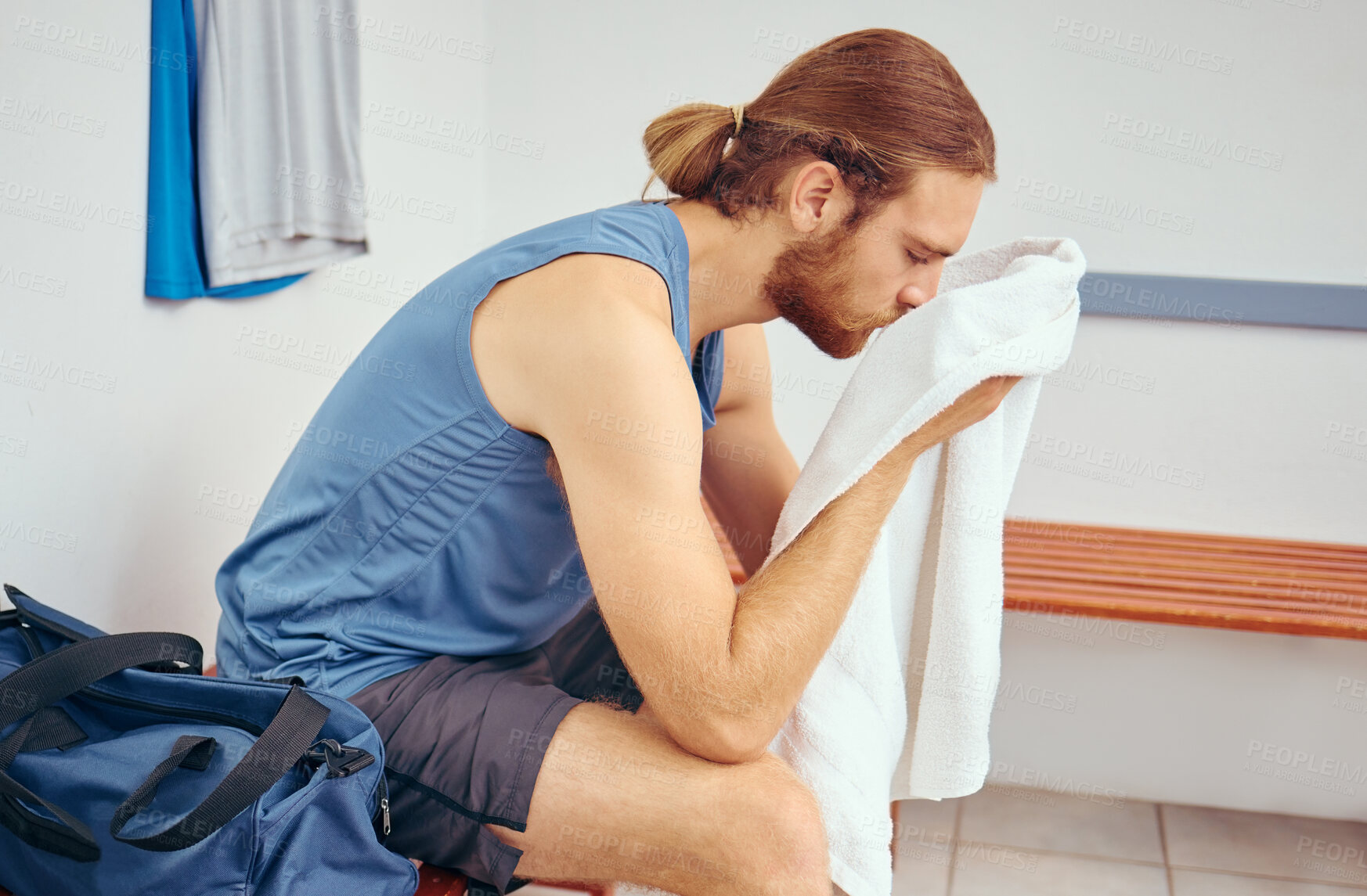 Buy stock photo Caucasian player wiping his face with a towel. Tired young player wiping his face after a squash match. Professional athlete taking a break from his squash match to rest in a gym locker room