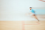 Young athletic squash player running while playing court game with copyspace and motion blur. Fit mixed race athlete moving with speed during training practice in sports centre. Sporty hispanic man