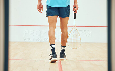Rear view of unknown squash player walking alone on court and holding racket before game. Fit active mixed race athlete getting ready for training and practice in sports centre. Sporty hispanic man