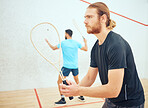 Young athletic squash player getting ready for playing opponent in competitive court game. Fit active caucasian athlete looking focused during training challenge in sports centre. Waiting for serve