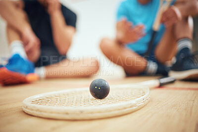 Buy stock photo Closeup of squash equipment and gear on wooden floor in court with players in background at sports centre. Racket and ball arranged in sporty arena after training practice and game. Resting and break