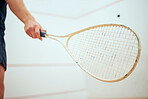 Unknown athletic squash player using a racket to hit the ball during a game on the court. Fit active caucasian male athlete training and playing in a sports centre alone. Healthy cardio and sporty man