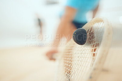 Closeup of unknown athletic squash player using a racket to hit a ball during a court game. Fit active mixed race male athlete training and playing in a sports centre. Healthy cardio and motion blur
