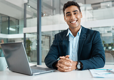 Buy stock photo Young happy mixed race businessman looking ready for the day while working on a laptop alone at work. One hispanic businessperson smiling while working at a desk in an office