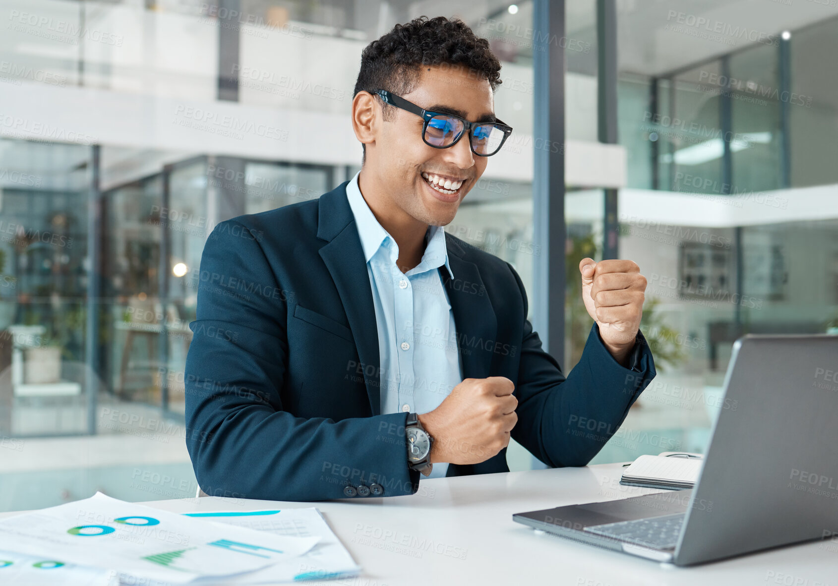 Buy stock photo Young mixed race businessman cheering with joy while working on a laptop alone at work. One hispanic businessperson smiling and celebrating success working at a desk in an office
