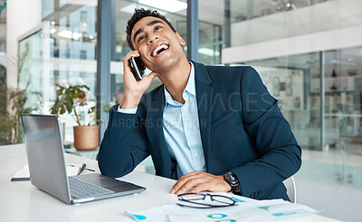 Buy stock photo Young joyful mixed race businessman talking on a call using a phone and thinking alone at work. One hispanic male businessperson talking on a cellphone and working on a laptop in an office