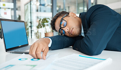 Buy stock photo Young mixed race businessman napping and working on a laptop at a table alone at work. One tired hispanic businessperson sleeping working at a desk in an office