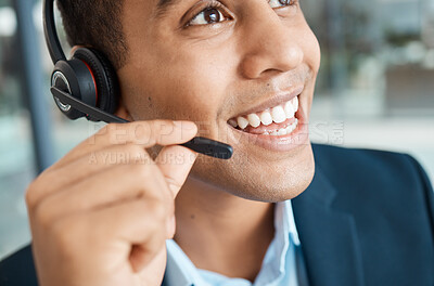 Closeup of a young happy mixed race male call center agent answering calls while wearing a headset and thinking alone at work. Face of a hispanic male assistant smiling while talking on a call at a desk in an office