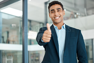 Buy stock photo Young happy mixed race businessman showing a thumbs up standing alone at work. One pleased hispanic businessperson smiling while showing support with a thumbs up in an office