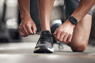 Buy stock photo Closeup of one mixed race man tying his shoelaces while exercising in a gym. Guy fastening sneaker footwear for a comfortable fit and to prevent tripping during a training workout in a fitness centre