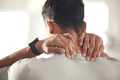 One mixed race man from behind holding his sore neck while exercising in a gym. Guy suffering with painful injury from fractured joint and inflamed muscles during workout. Struggling with stiff body cramps causing discomfort and strain