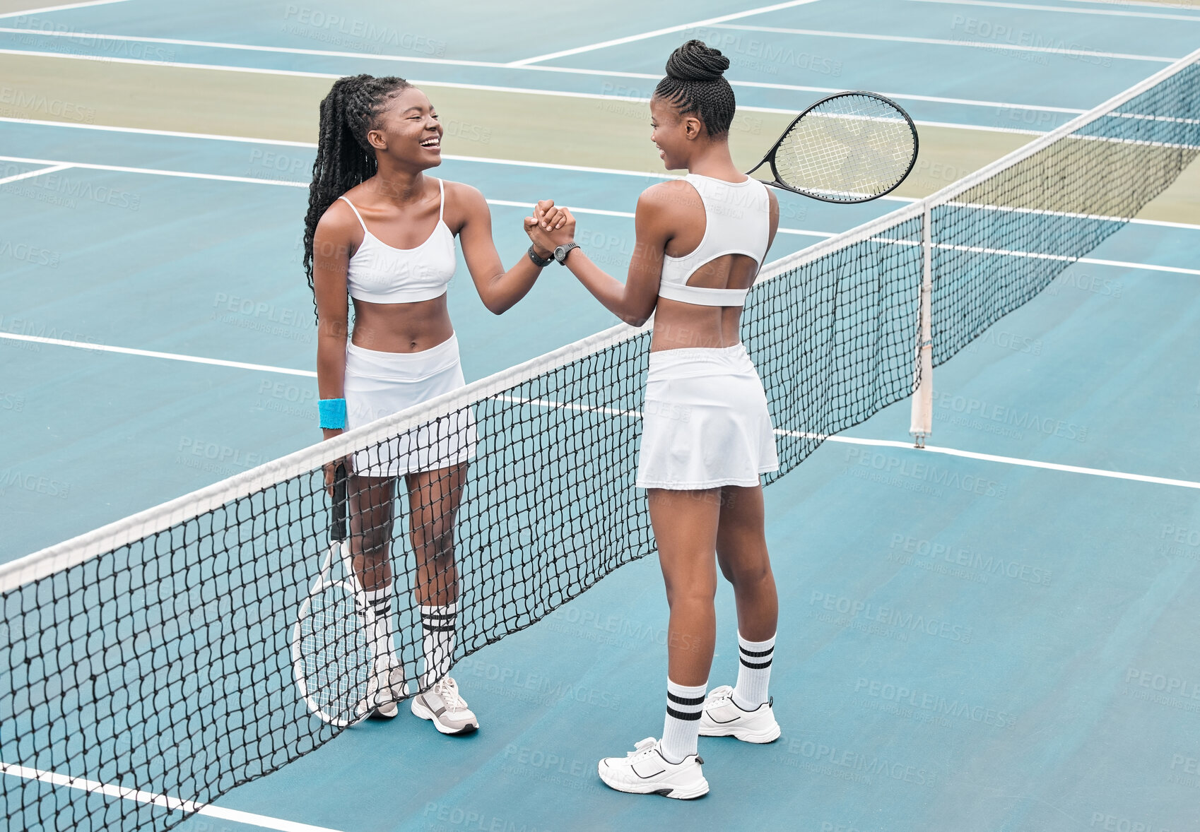 Buy stock photo Professional tennis players giving each other a handshake. African american friends bonding after a game on the court. Carefree young women greeting each other on the tennis court