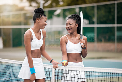 Buy stock photo Two friends talking and laughing after a tennis match. Young women bonding after a game of tennis. Professional tennis players walking next to the net on the court. Girls bonding after a game