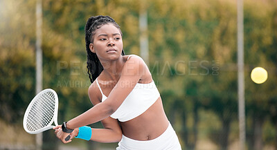 Buy stock photo Young girl waiting to hit a ball in a tennis match. African american woman enjoying a game of tennis. Serious young woman playing tennis on her club court. Active, fit player hitting a tennis ball