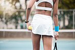 Back of a tennis player holding her racket on the court. African american tennis player holding her ball and racket on the court. Professional tennis player ready for a game of tennis